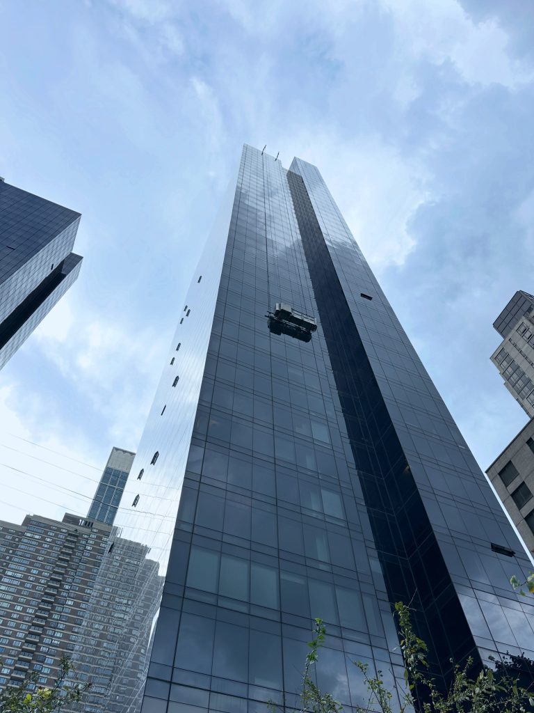 Glass Manhattan tower with a window cleaning gondola on its facade, seen from the street