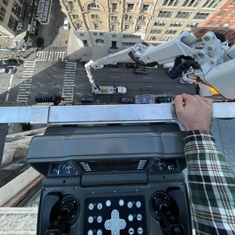 Lift operator at the basket controls high above a Manhattan street