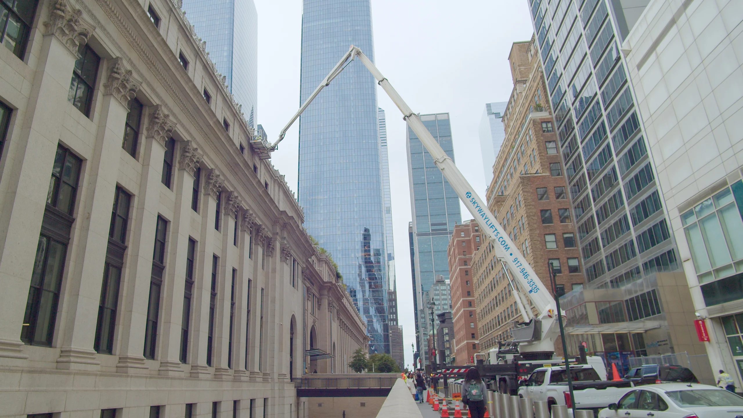 Truck-mounted lift cleaning a historic facade next to a glass tower
