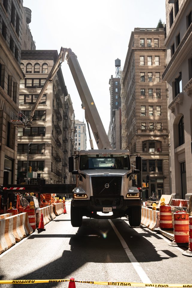 Skyway truck-mounted aerial lift working on a Manhattan street, with barriers, cones and caution tape securing the work zone