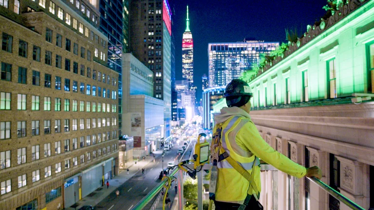 Skyway technician on an aerial lift above Midtown Manhattan at night