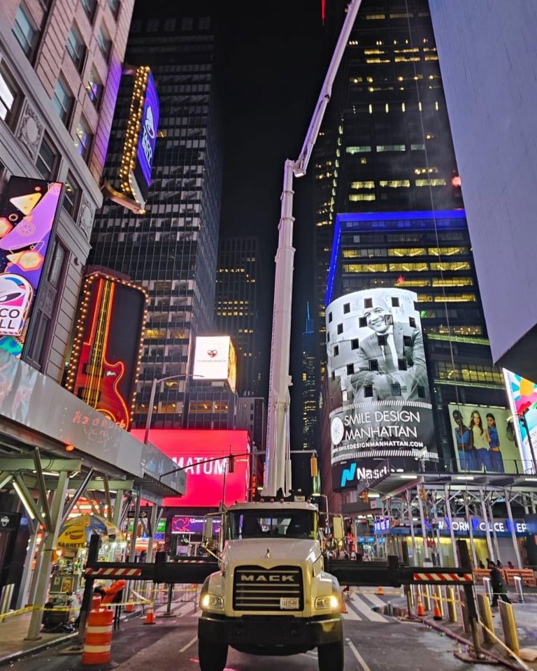 Skyway truck-mounted lift cleaning windows above Times Square at night