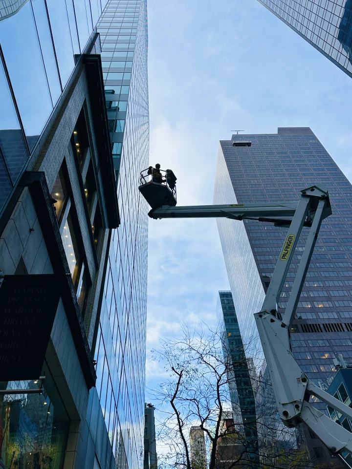 Technician in an aerial lift basket between glass office towers