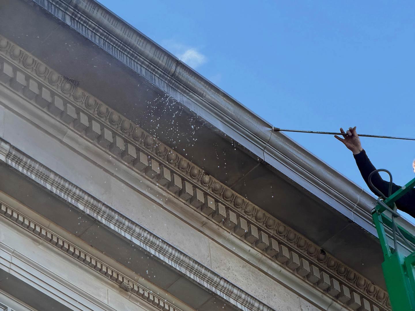 Skyway technician washing a building cornice with a water-fed pole
