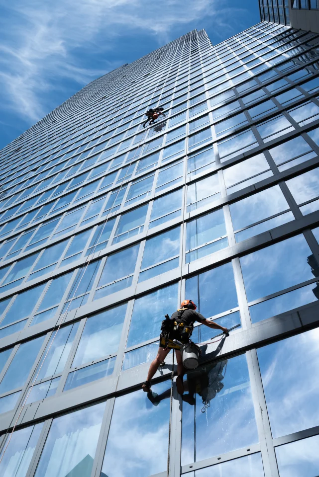 Rope access window cleaner on a glass curtain wall