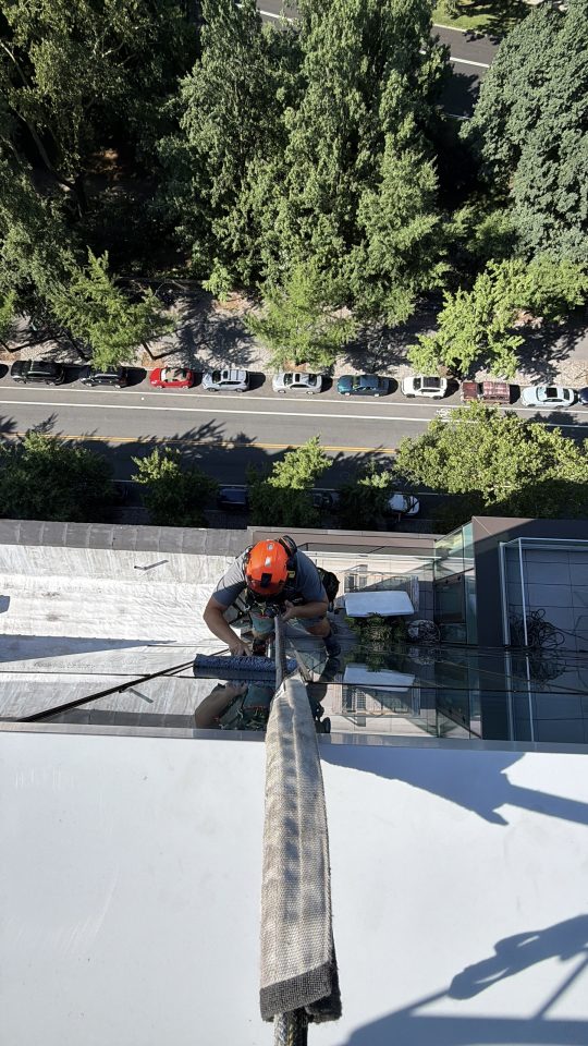 Skyway rope access technician working on a building ledge high above a New York street