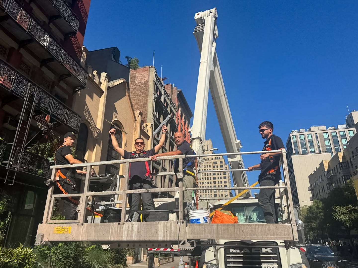 Skyway crew in a truck-mounted lift basket beside a New York building facade