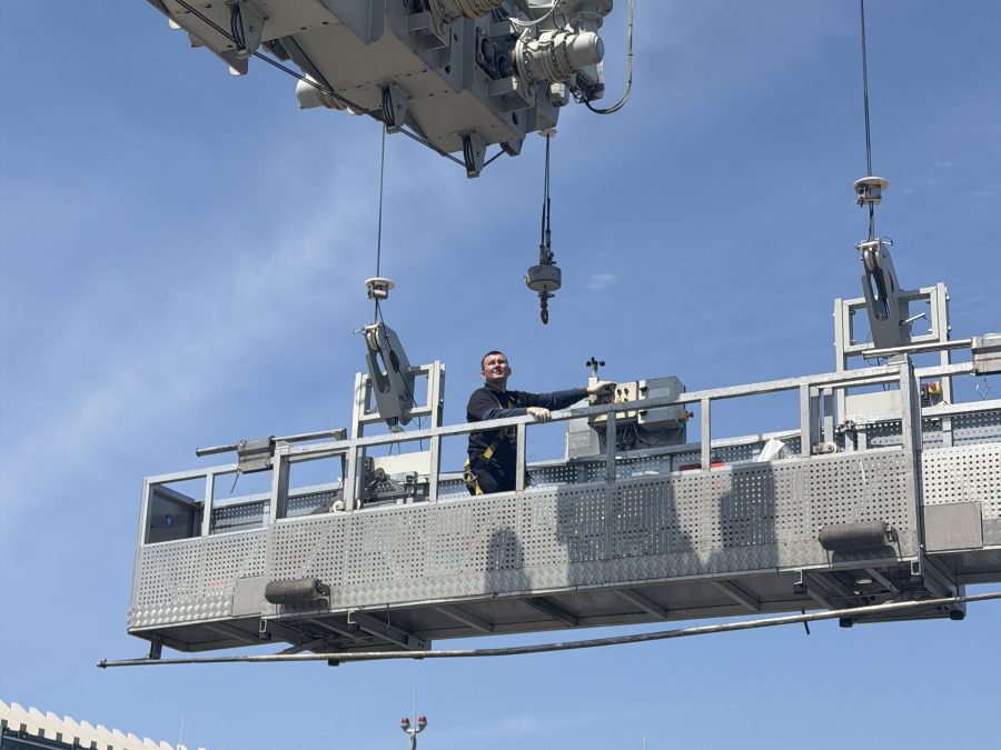 Skyway window cleaner on a suspended scaffold hanging from a high-rise roof